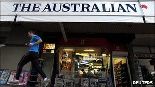 A man in Sydney runs past an advertising banner for The Australian newspaper which is published by News Limited