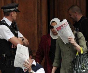 Women emerging from the Libyan embassy in London cover their faces as a British policeman looks on, 27 July