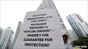 A demonstrator holds a placard outside the venue of the signing ceremony between Malaysia and Australia to swap refugees in Kuala Lumpur on 25 July 2011