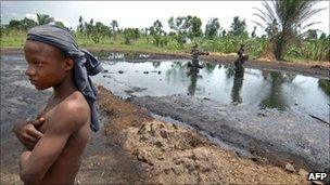 Boy stands near an abandoned oil well head leaking crude oil, 11 April 2007, in Kegbara Dere, Ogoni Territory