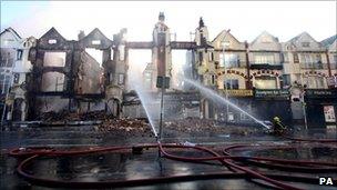 Fire crews douse burnt out buildings on London Road in Croydon, Surrey