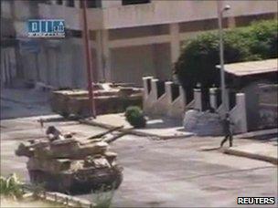 A soldier walks near an army tank on a street purportedly in Hama (Still image taken from amateur video on 7 August 2011)