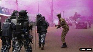 Riot policemen run through a cloud of coloured teargas to disperse supporters of Uganda's opposition marching on a street in Masaka town, 120 km (72 miles) southwest of the capital Kampala August 10, 2011.