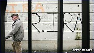Man walking by IRA graffiti
