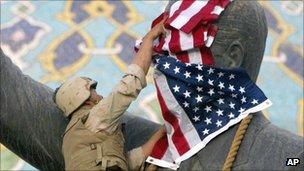 US marine covers the face of Saddam Hussein with an American flag