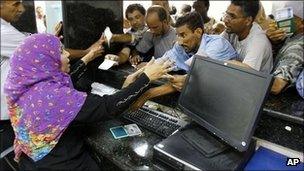 People rush to get cash from their accounts after the Libyan banks reopen