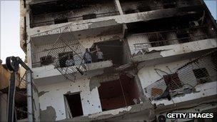 People stand on a damaged balcony of a war torn building on Tripoli Street, on September 03, 2011 in Misrata