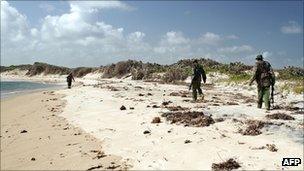 Armed policemen patrol a stretch of beach near Kiwayu Safari village
