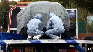 Police forensic officers cover a car