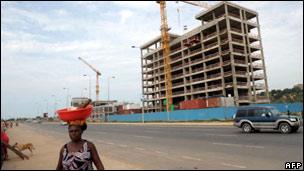 A woman walks past a construction site in Luanda, Angola, in January 2010