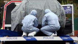 Police forensic officers examining a car