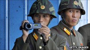 North Korean soldiers look and film footage of the South side of the Demilitarized Zone