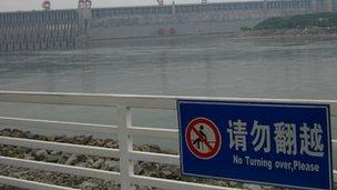 A sign in front of a river that reads "no turning over, Please"