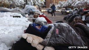 A protester, his sleeing bag covered in frost, sleeps on the sidewalk at the Occupy Denver camp on 27 October 2011