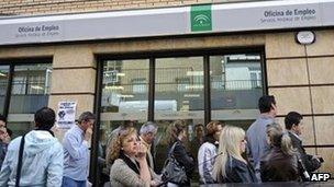 People queue outside an employment office in Seville, Spain