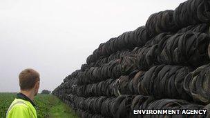 Man looks at stockpile of tyres in a field