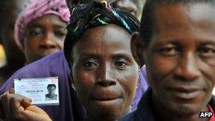 A woman shows her voter card as she waits in a queue in Monrovia to cast her ballot (8 November)