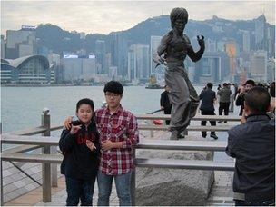 Tourists pose for pictures in front of the statue of martial arts movie star Bruce Lee