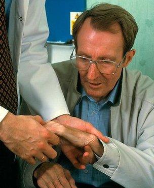 A doctor examines the hands of a man with Parkinson's disease