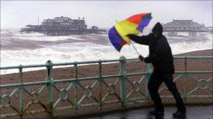 Man with brolly in strong winds on Brighton seafront