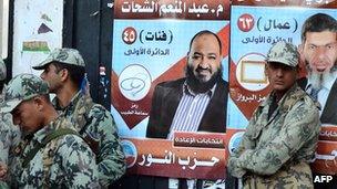 Egyptian soldiers stand in front of campaign posters for candidates from the hardline Islamist Salafist Al-Nur Party, in the coastal city of Alexandria on 5 December 2011.