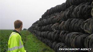 An Environment Agency officer looks at a huge line of tyres as far as the eye can see