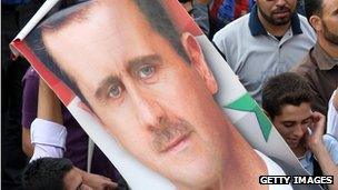 Demonstrators hold up a poster of President al-Assad