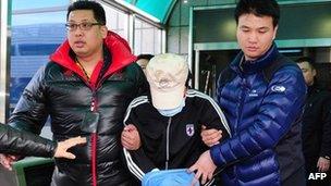 A fishing captain suspected of murdering a South Korean coast guard is taken by South Korean maritime police at a hospital in Incheon, west of Seoul, on December 12, 2011.