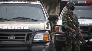 A masked Mexican navy marine keeps custody of police vehicles outside of a police station after the entire police force was disbanded in the Gulf port city of Veracruz, Mexico