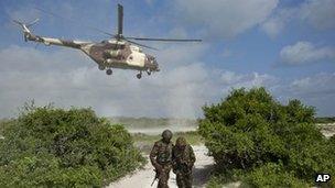 In this Wednesday, Dec. 14, 2011 file photo, two Kenyan army soldiers shield themselves from the downdraft of a Kenyan air force helicopter as it flies away from their base near the seaside town of Bur Garbo, Somalia.