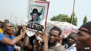 Protesters carrying mock coffin of President Goodluck Jonathan reading "Rest in Pains"