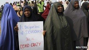 Muslim women holding placards asking what kind of democracy is this?