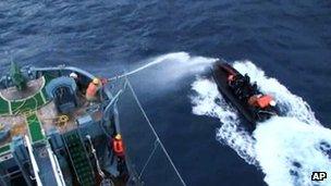 Screen image from video provided by Japan's Institute of Cetacean Research showing a crew member on the Japanese whaling ship Yushin Maru No 2 spraying water cannon towards Sea Shepherd Conservation Society activists aboard a rubber boat in Antarctic waters on 18 January 2012