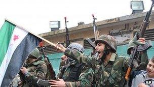 A Syrian army defector waves the Syrian revolution flag in Homs province, on Thursday, Jan. 26, 2012