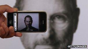 A photographer takes a picture with his own iPhone of a Steve Jobs tribute in London, United Kingdom in 6 October 2011