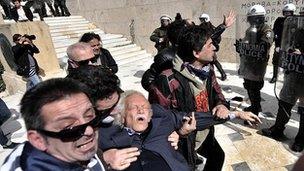 Manolis Glezos is assisted by protesters outside the Greek parliament in Athens in March 2010