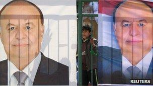 A boy stands between posters of Yemeni Vice President Abdrabbuh Mansour Hadi during an election rally in Sanaa