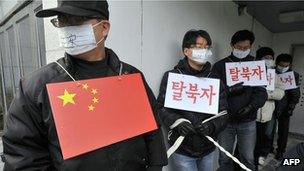 South Korean rights activists perform role of mock Chinese police and North Korean refugee outside the Chinese embassy in Seoul on 21 February, 2012