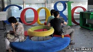 People sit on a sofa in front of a Google logo
