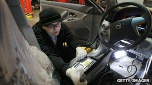 A worker checking brake pedals in a Toyota Camry car