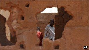 A man is seen through a hole punched out by gunfire in an abandoned home that took heavy fire during a military operation to free two hostages in Sokoto, Nigeria