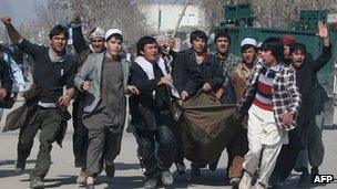 Afghan demonstrators carry a counded man as they protest against Koran desecration in Kunduz, february 25