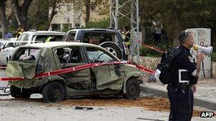 Israeli policeman stands near a car in Ashdod damaged by a rocket fired by militants in Gaza (12 March 2012)
