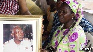 Relatives of slain Guinea Bissau ex-military intelligence chief Samba Djalo mourn his death next to a portrait of him in the capital Bissau, March 19, 2012.