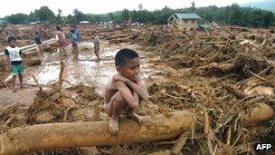 Child sits on tree in flood