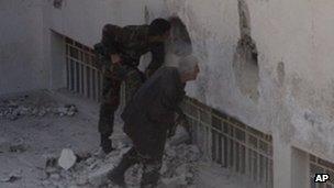 Two soldiers with guns looking through a hole in a concrete wall
