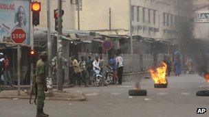 A soldier participating in a mutiny stands near civilians and burning tires lit in support of the mutiny, in Bamako, Mali on 21 March