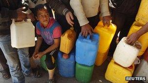 Children wait with their containers at a petrol station in Khan Younis, 22 March 2012.