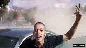 Image of Mohamed Merah next to a car, waving his hand in the air