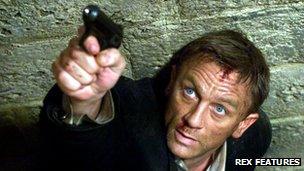 Daniel Craig aiming a gun in character as the fictional spy James Bond